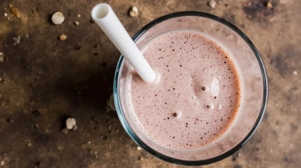 Close up view of a creamy strawberry smoothie with smooth texture and light pink color.