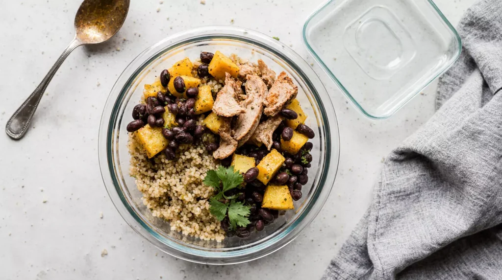 Easy microwave meal prep bowl with quinoa, beans, vegetables, and chicken in a glass container